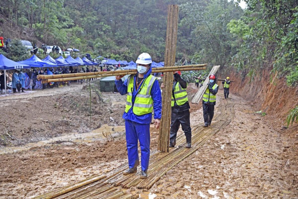 Các nhân viên cứu hộ vác tre để đặt trên một con đường dẫn vào địa điểm máy bay rơi ở huyện Đằng, thành phố Ngô Châu, khu tự trị dân tộc Choang Quảng Tây, Trung Quốc hôm 23/3. Ảnh: Tân Hoa Xã