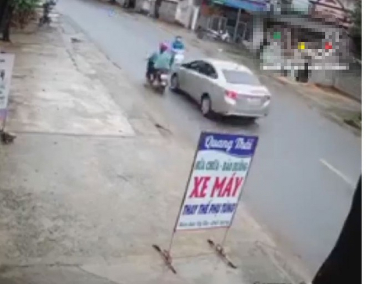 Hình ảnh người phụ nữ điều khiển xe máy màu trắng trước đầu ô tô con trước khi bị đâm