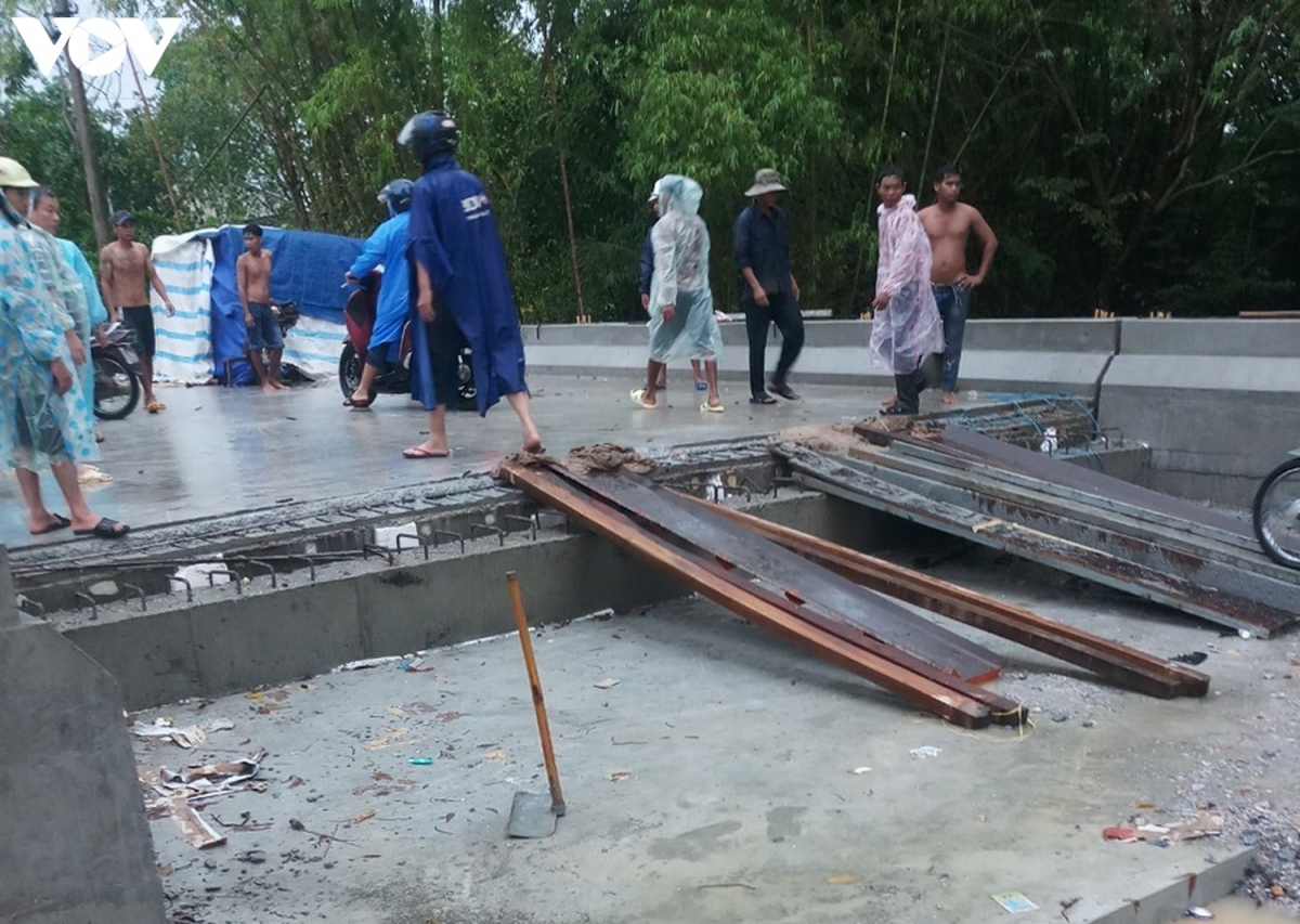 Người dân bắc ván cho các xe máy đi tạm trên cây cầu đang thi công dang dở bên cạnh cầu tạm./.