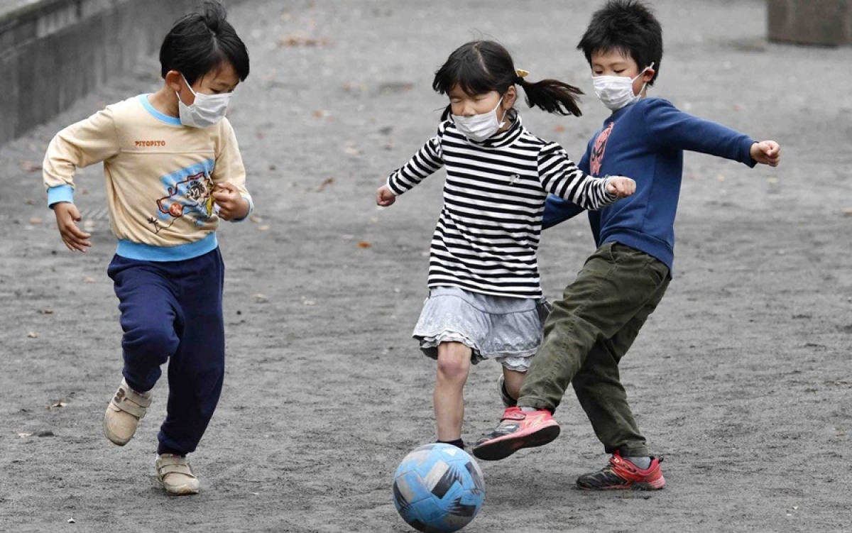 Trẻ em Nhật đeo khẩu trang khi đá bóng. Ảnh: Kyodo.