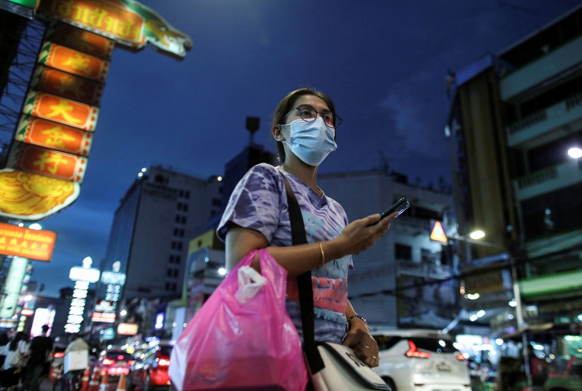 Một phụ nữ đeo khẩu trang phòng chống Covid-19 đang đi trên đường phố Bangkok (Ảnh: Reuters).