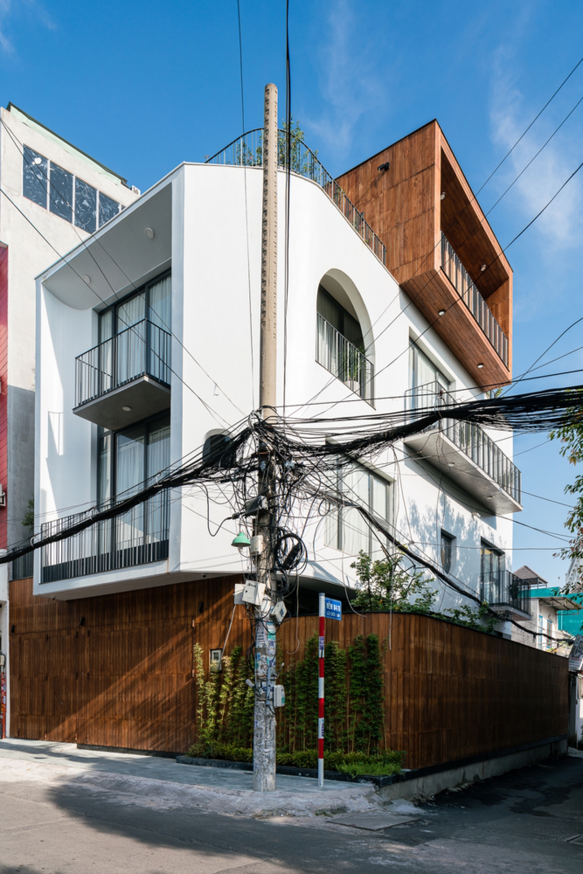 Ngôi nhà có lớp tường rào dày để ngăn tiếng ồn không mong muốn từ phố xá tấp nập, cùng những mảng tường ốp gỗ để khéo léo che giấu hệ thống cửa.