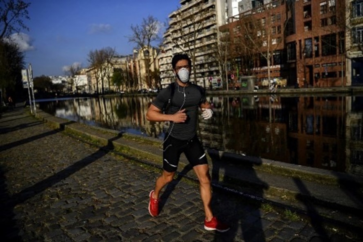 Để ngăn chặn dịch Covid-19 ở Pháp, Paris phát lệnh bắt buộc đeo khẩu trang ở ngoài trời. Trong ảnh là người đàn ông đeo khẩu trang chạy bộ dọc kênh Saint-Martin ở Paris. Ảnh: AFP.