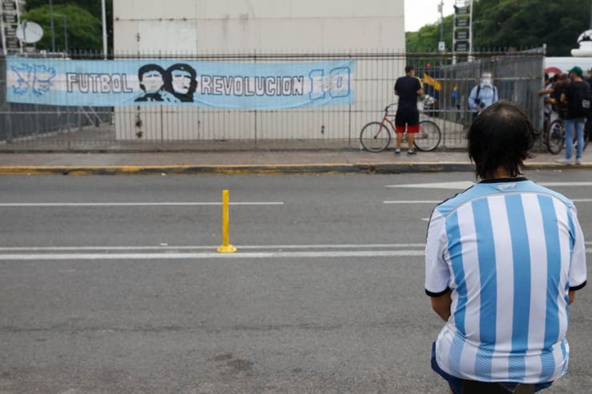 Một cổ động viên buồn bã ngồi tưởng nhớ Diego Maradona.