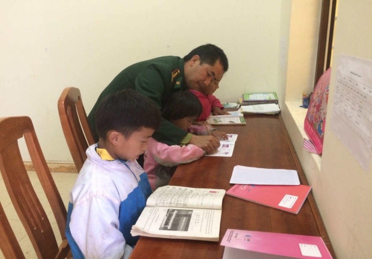 Đại úy Vừ Mí Chứ hướng dẫn các con học bài. (Ảnh: NVCC)