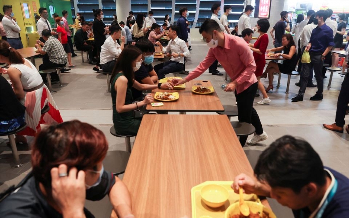Nhân viên văn phòng tại nơi ăn trưa sau khi dỡ bỏ hạn chế phòng Covid-19. Ảnh: Reuters.