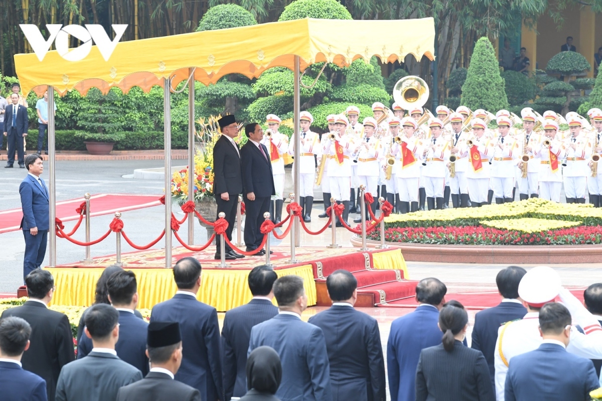 PM Chinh invites his Malaysian counterpart to step on the podium while military bands play the national anthems of both nations.
