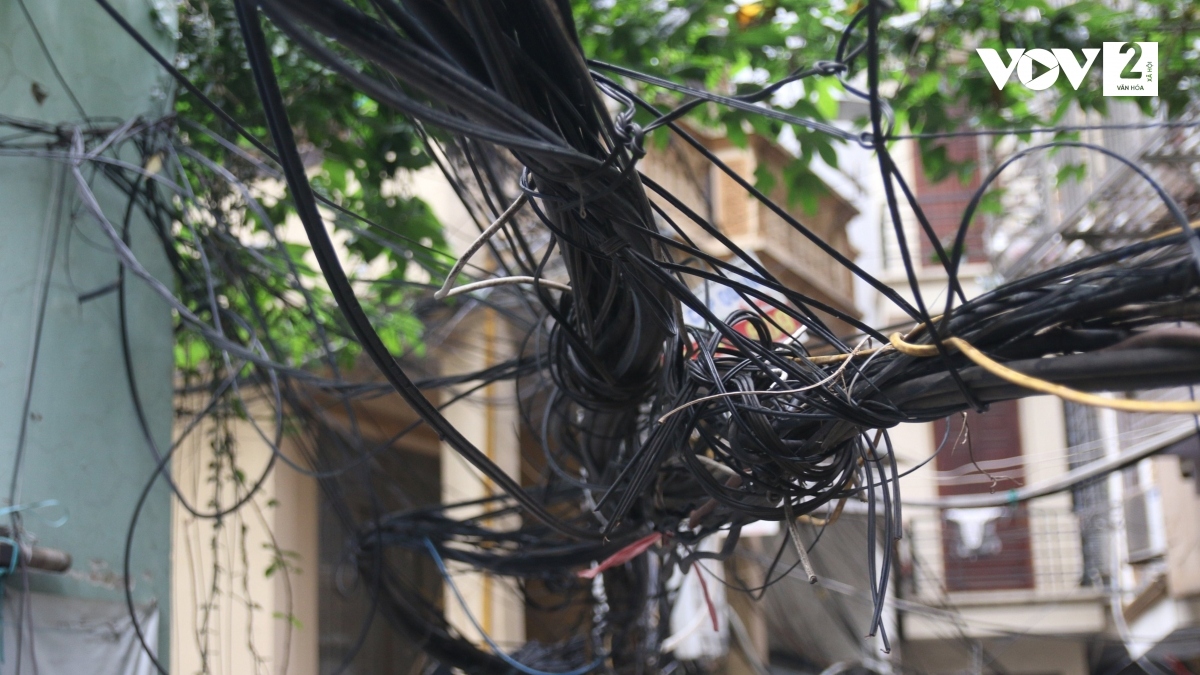 Những cuộn dây điện, cáp viễn thông giăng ngang dọc đe doạ an toàn của người dân.