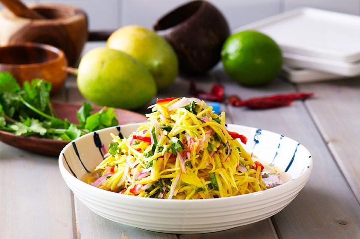 Nộm đu đủ xoài xanh (green papaya &amp; mango salad) combines raw, green papaya, and ripe mangoes. The julienned green papaya provides a crunch and tang to the salad, while the juicy ripe mangoes contribute to the rich sweetness of the dish. The salad is often adorned with an array of aromatic herbs such as cilantro and mint, which serve to infuse the dish with a delightful fragrance. The dish is a celebration of the nation’s depth of fresh ingredients.