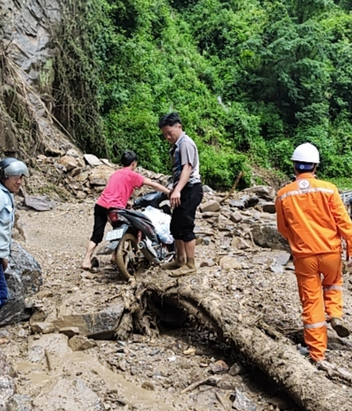 Công nhân Điện lực tại Sơn La hỗ trợ người dân qua khu vực sạt lở.