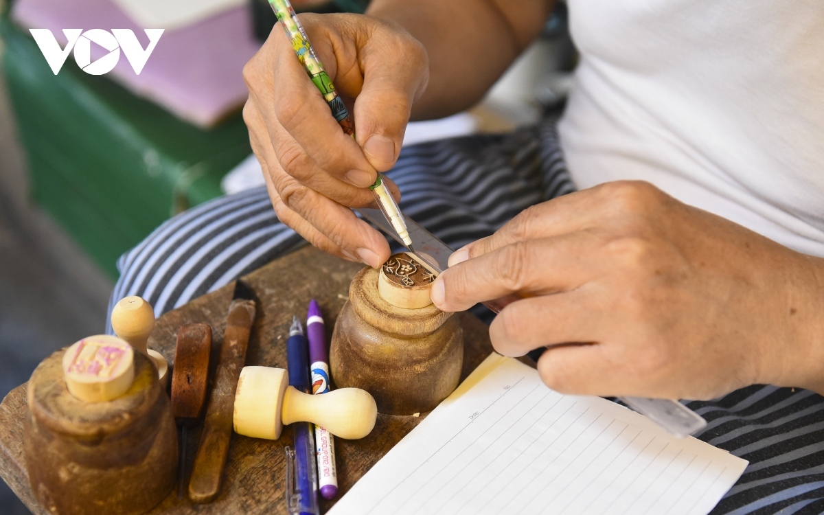 He outlines customers’ ideas before making the wood stamp.