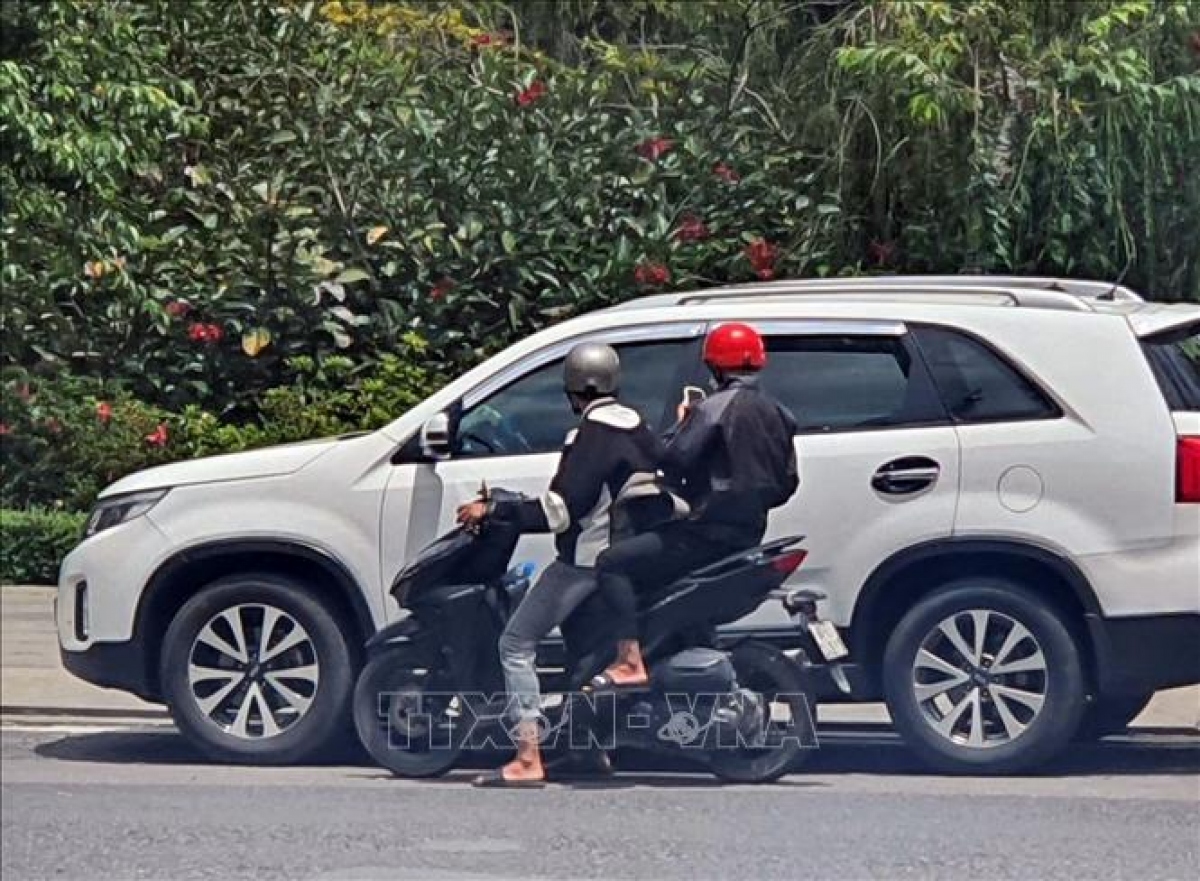 2 đối tượng dán tờ rơi có nội dung khiêu dâm trên kính xe ô tô. Ảnh: TTXVN phát