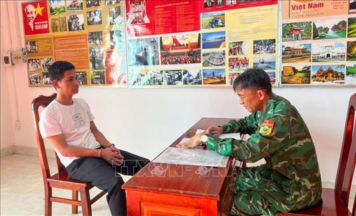 Cán bộ Đồn Biên phòng cửa khẩu quốc tế Mộc Bài lấy lời khai Phạm Ngọc Tài. (Ảnh: TTXVN)