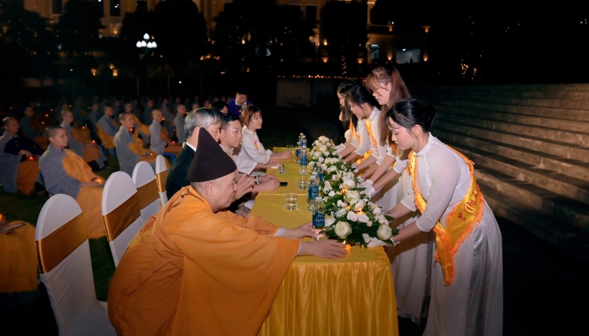 Young girls in a white long dress offer flowers to show their respect and gratitude to superior monks, distinguished guests and parents.
