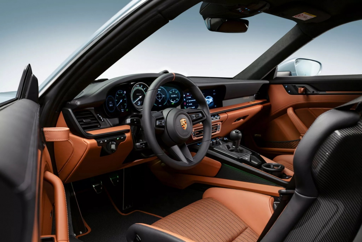 Bên trong, ghế CFRP là trang bị tiêu chuẩn, có thể đổi chỗ cho các ghế Sport Seat Plus. Cụm đồng hồ và đồng hồ của gói Sport Chrono (Thể Thao) trên Porsche 911 S/T 2024 sở hữu tông màu xanh cổ điển của Porsche.