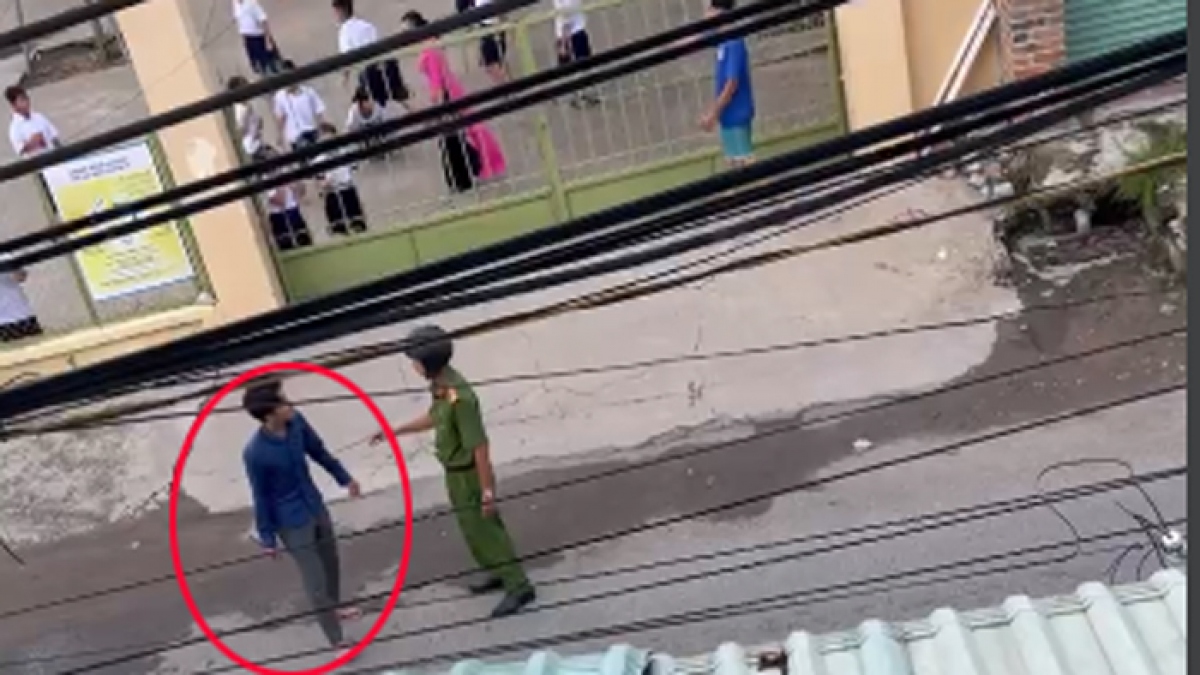 Đối tượng cầm dao đứng trước cổng trường học. (Ảnh: Cắt từ video)