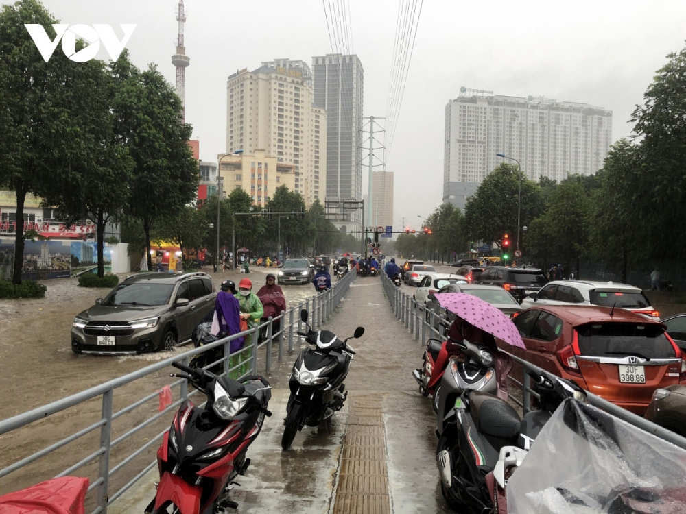 The torrential rain falls during rush hours, causing traffic to grind to a halt. The photo has been snapped on To Huu Street.
