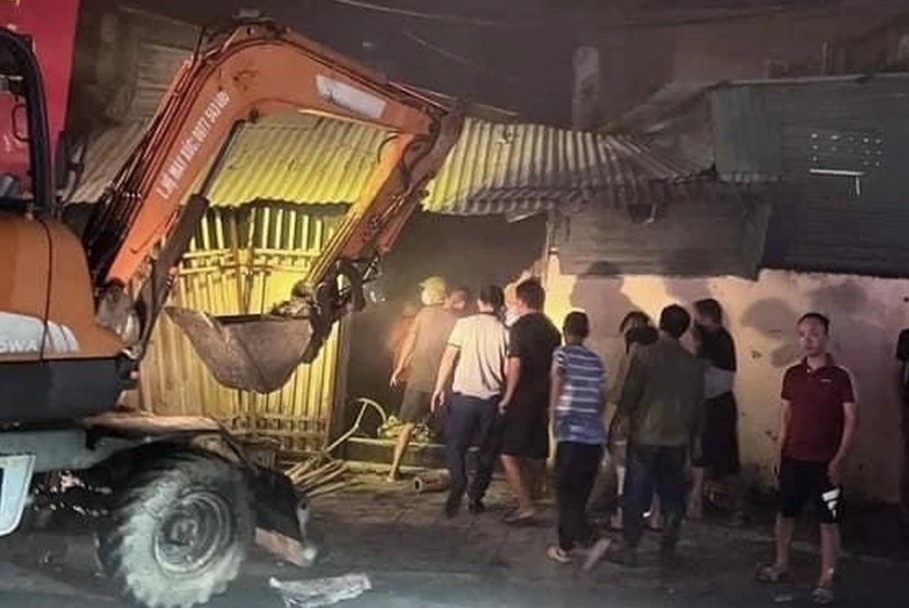 Máy xúc phá tường giúp mọi người dễ dàng tiếp cận đám cháy (Ảnh: Hoàng Ngân)