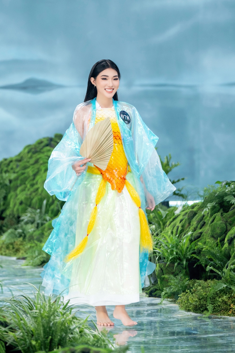 Quạt làm từ lá cọ khô, còn phần còn lại của trang phục được làm từ túi nilon, vỏ chai nhựa, vải giấy tái chế… Thí sinh Trương Thị Thùy Trang tiết lộ đây là một mẫu thiết kế được được lấy cảm hứng từ Việt Phục- những bộ trang phục của người Việt Nam qua các thời kỳ lịch sử.