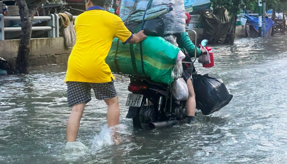 Do nước ngập sâu, có nơi ngập hơn nửa bánh xe khiến một số phương tiện bị chết máy giữa đường. Người dân trong khu vực hỗ trợ bằng cách đẩy xe lên lề đường.
