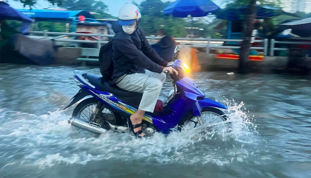 Một người dân vội vã tăng ga chạy qua vùng ngập để thoát khỏi đoạn đường bị ngập.