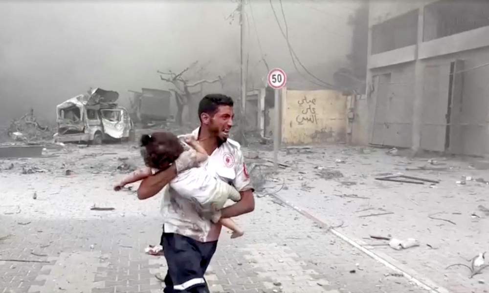 Người đàn ông bé một đứa trẻ ở Gaza bị thương. Ảnh: Reuters