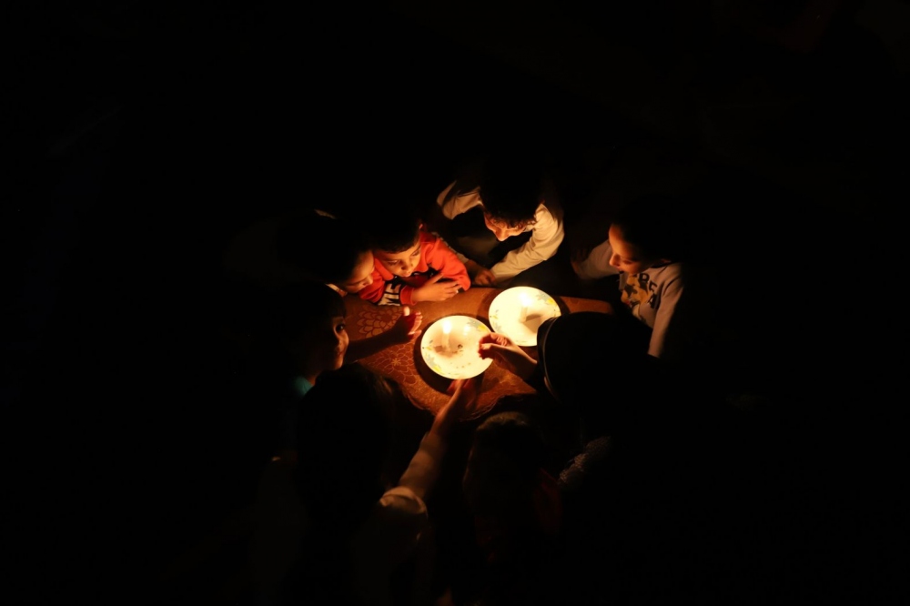 Những đứa trẻ tại Gaza tập trung quanh ánh nến. Điện, nước, viễn thông... đã bị cắt hoàn toàn tại đây.