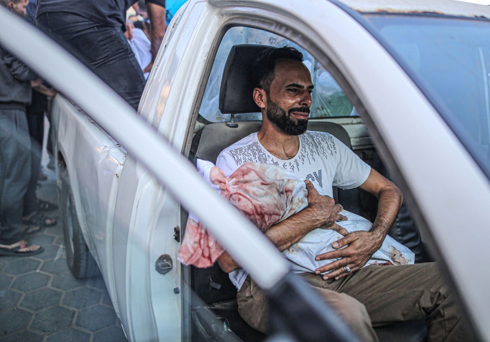 Người đàn ông Palestine nhận thi thể người thân từ ​​Bệnh viện Al Aqsa ở Deir Al-Balah, Gaza, vào ngày 31/10. 