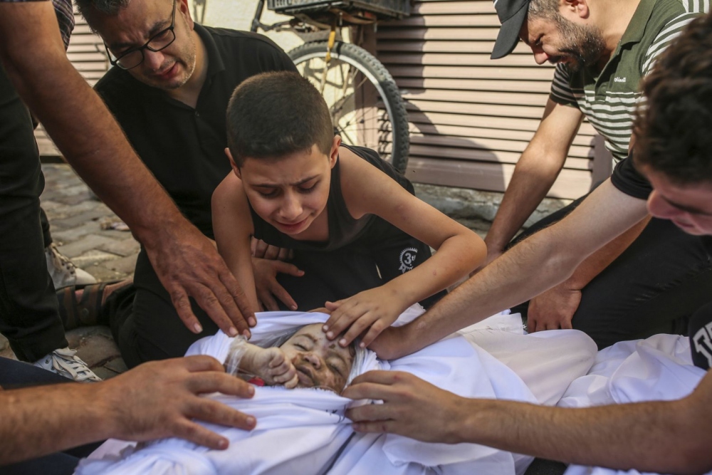 Cậu bé Khaled Joudeh khóc bên thi thể em gái Misq tại nhà xác bệnh viện Deir Al-Balah ở Gaza ngày 22/10.