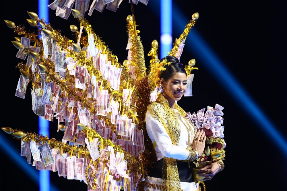 Trang phục dân tộc của Hoa hậu Myanmar lấy cảm hứng từ một truyền thống trong cộng đồng Phật giáo, nơi một phần tiền tiết kiệm của một gia đình hoặc cá nhân được quyên góp cho tu viện địa phương.