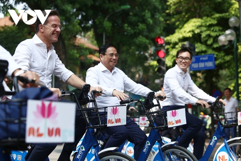 The two PMs cycle through the tree-lined streets of Hanoi such as Phan Dinh Phung, Nguyen Tri Phuong, and Ton That Dam, waving to people on both sides of the streets.