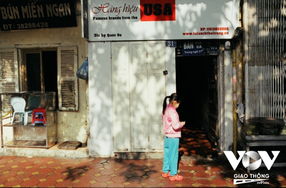 Một cô bé đứng chơi trước cửa nhà ở phố Lý Quốc Sư trong ngày chớm đông, khi nhiệt độ bắt đầu lạnh nhưng vẫn có nắng nhẹ...