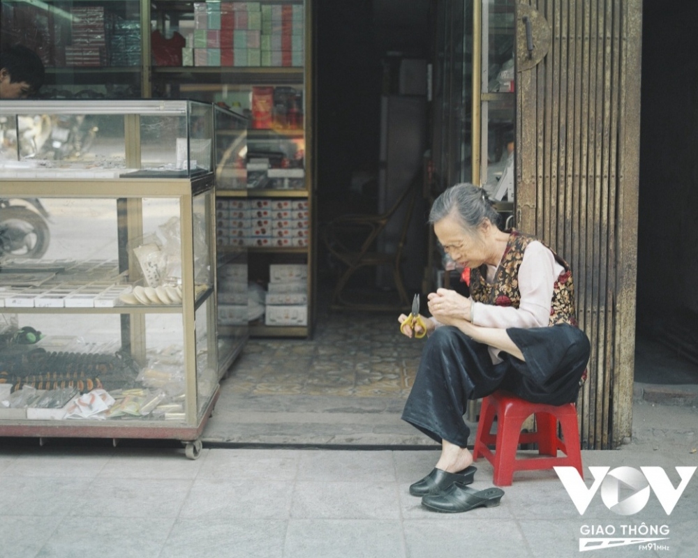Cụ bà ngồi thư giãn trước cửa nhà trên phố Hàng Bạc