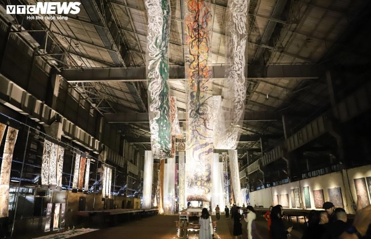 An installation art exhibition titled "The Call" by artist Thu Tran features 40m - 60m long strips of paintings hung on the ceiling.