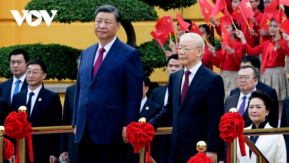 Party General Secretary Nguyen Phu Trong invites Party General Secretary Xi Jinping to the podium for the flag salute ceremony.