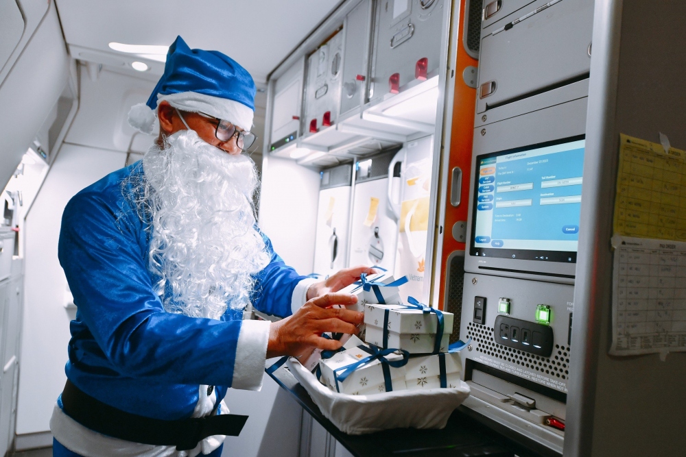Trong lúc chờ hành khách dùng xong bữa ăn Giáng Sinh, các “ông già Noel” đang tất bật chuẩn bị quà tặng.
