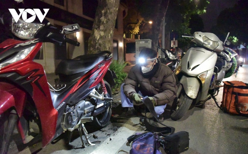 A worker is busy repairing motorbikes at night.