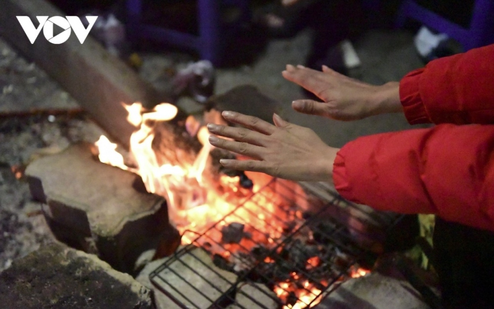 Street vendors burn firewood as they try to warm themselves in the cold winter.