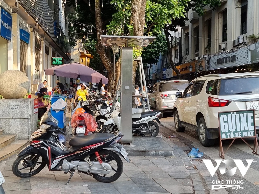 Một điểm trông giữ xe khác tại đầu phố Đinh Lễ giao phố Đinh Tiên Hoàng (Hoàn Kiếm, Hà Nội). Biển trông giữ xe được đặt ngay trên ở lòng đường để khẳng định chủ quyền cho bãi gửi xe của mình. Còn trên vỉa hè thì hàng dài xe máy đỗ, chắn hết vỉa hè