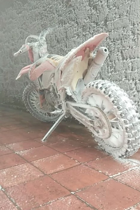 A motorbike is left covered in frost.