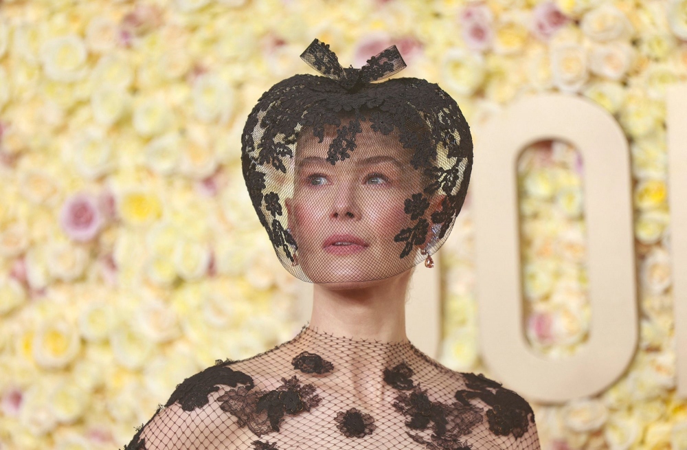Nữ diễn viên "Saltburn" Rosamund Pike quyết định kết hợp chiếc váy ren đen thời trang cao cấp mùa Thu 2019 của Dior với chiếc khăn che mặt quyến rũ của Philip Treacy.