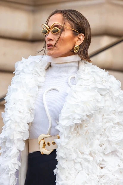 Jennifer Lopez debut mái tóc bob mới lạ tại show diễn Haute Couture của Schiaparelli. Cô diện một chiếc áo khoác được đính kết vô cùng tinh xảo và tỉ mỉ, khoác ngoài áo len cổ lọ và quần bó đen. Nữ nghệ sĩ không quên tạo điểm nhấn với cặp kính mắt độc đáo và chiếc túi Anatomy của Schiaparelli
