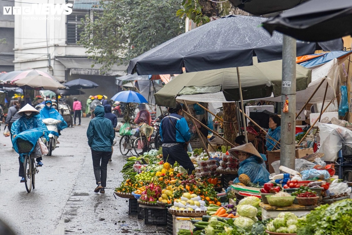 Không chỉ người mua mà ngay cả các tiểu thương ngồi dưới tán dù vẫn mặc áo mưa, đội nón để chống lại cái lạnh. Nhiệt độ Hà Nội lúc sáng sớm là khoảng 14-15 độ C.