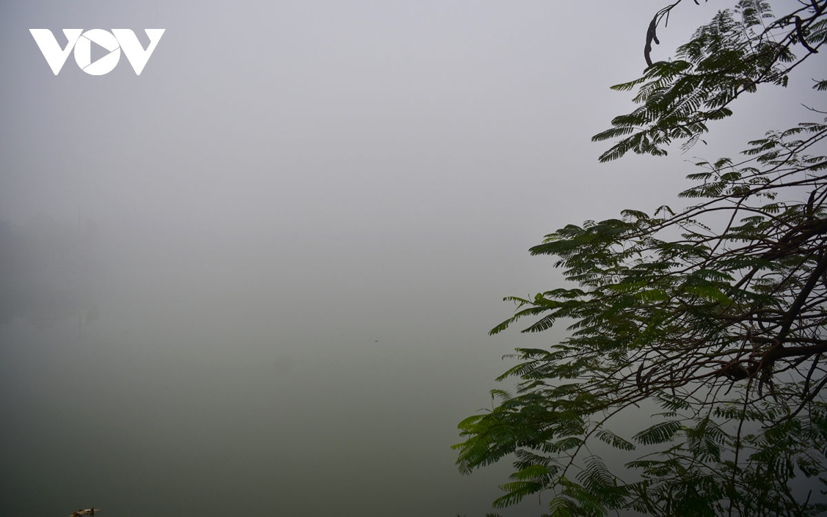 Motorcyclists travel slowly along Long Bien Bridge in Hanoi due to poor visibility.