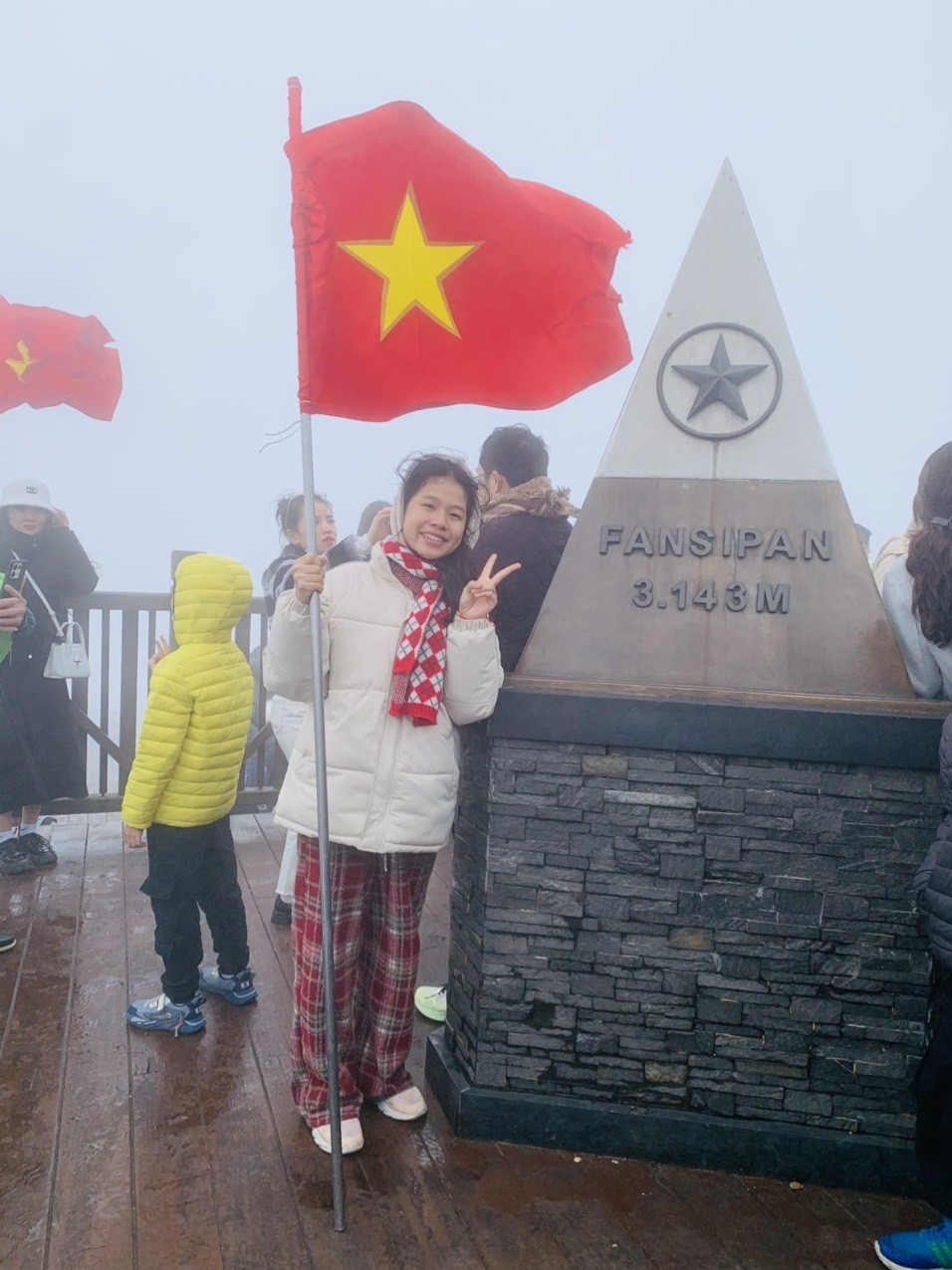 A young girl snaps a romantic photograph at the peak of Mt. Fansipan.