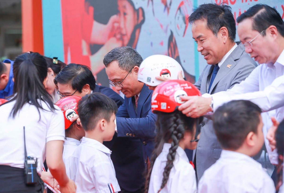 Các đại biểu trao tặng mũ bảo hiểm cho các em học sinh lớp Một trường Tiểu học Phú Đô