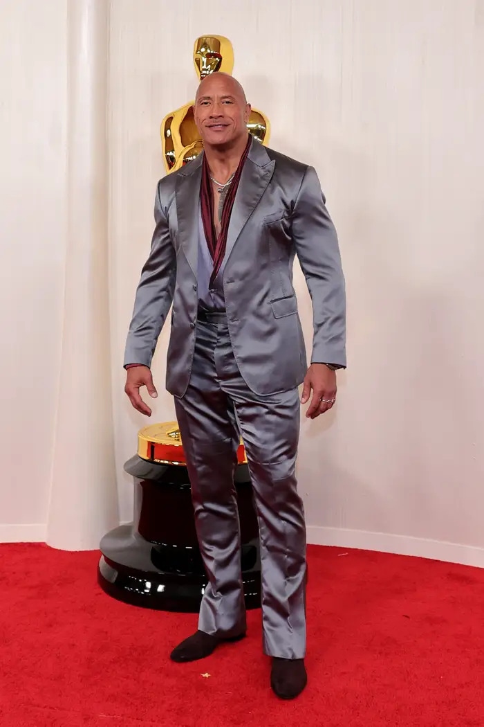 Dwayne Johnson bước đến thảm đỏ với bộ vest của Dolce &amp; Gabbana. Chất liệu satin trông như không được là lượt kỹ khiến cho ngôi sao trông lôi thôi trên thảm đỏ.