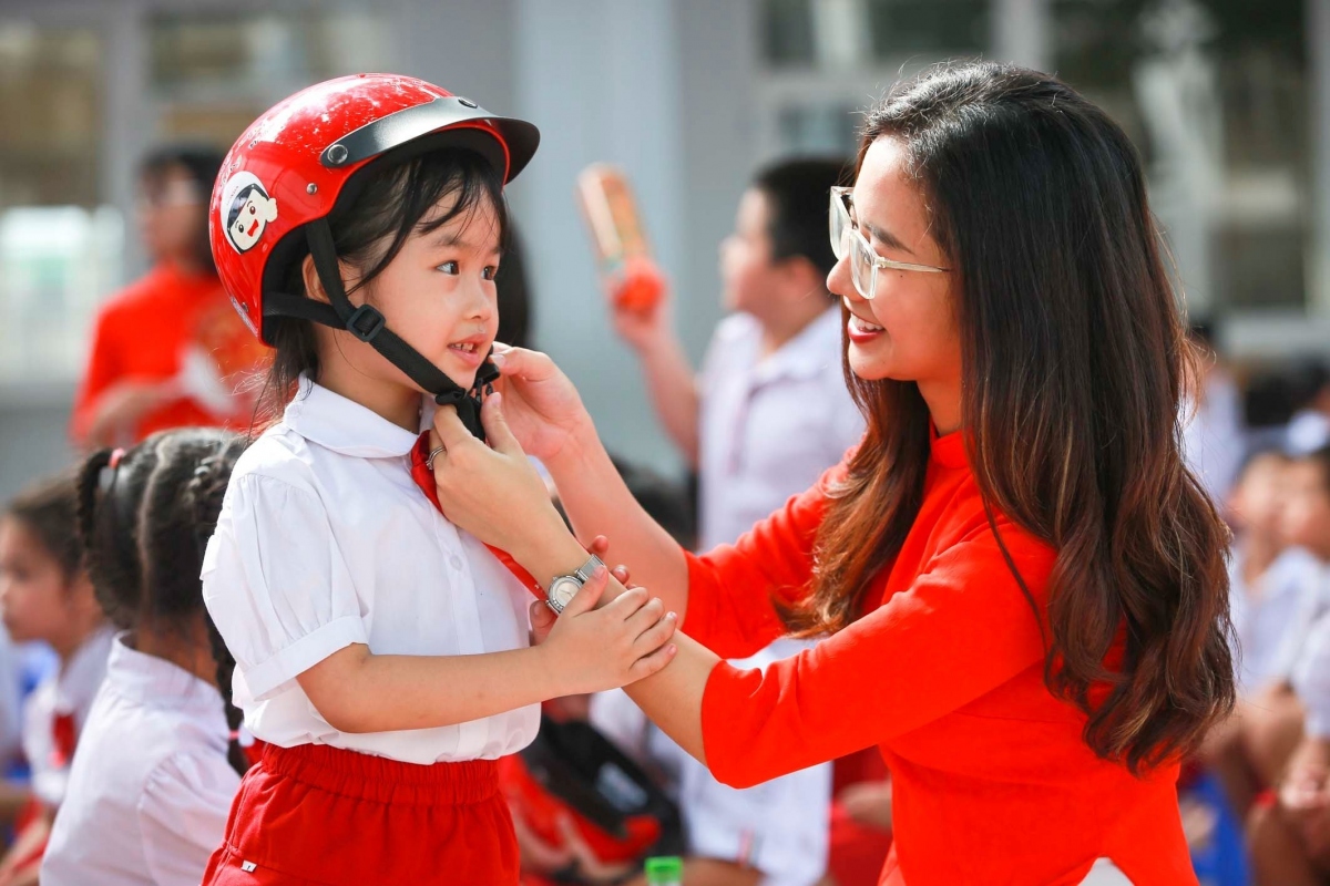 Giáo viên hướng dẫn các em đội mũ bảo hiểm đúng cách
