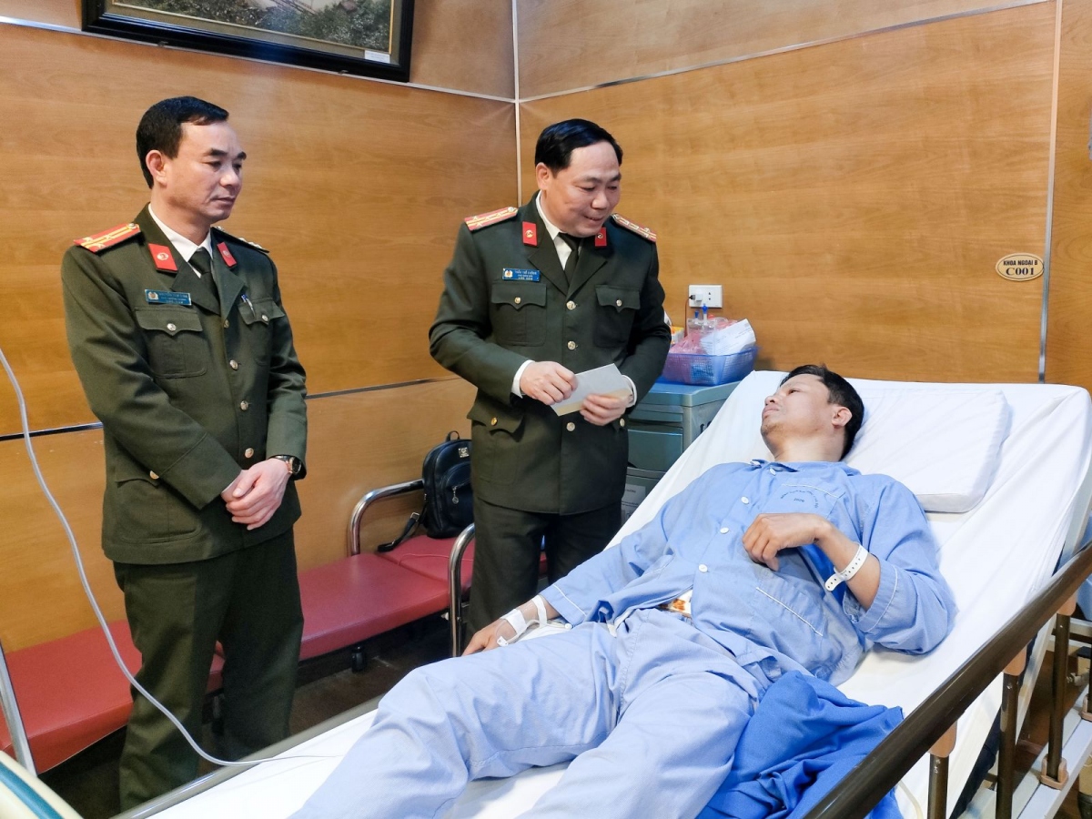 Đại tá Trần Thế Cường - Phó Giám đốc Công an tỉnh Bắc Giang (bên phải) thăm hỏi, động viên đồng chí Đoàn Thế Chí bị thương trong quá trình thực hiện nhiệm vụ