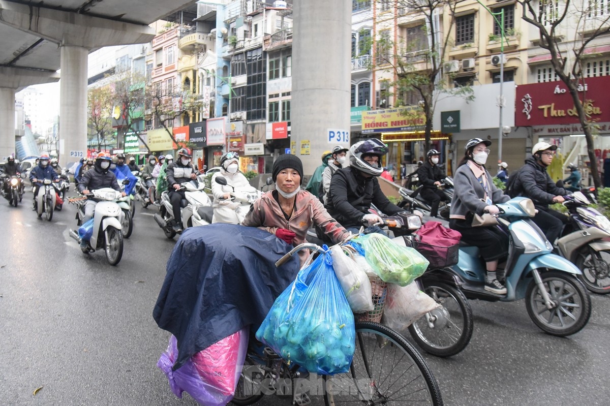 A street vendor uses raincoat to cope with the cold air and drizzly conditions.